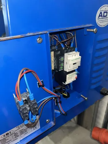 Failed electrical contactor inside the control panel of a Nilfisk DTE wall-mounted static pressure washer before replacement.